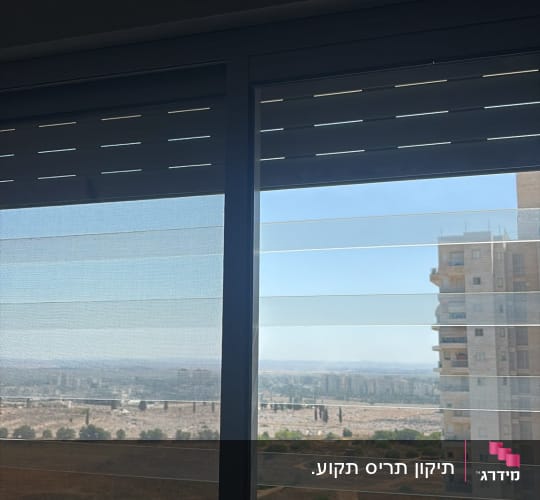 תריס גלילה ורשת בחלון הזזה אלומיניום עם נוף עירוני